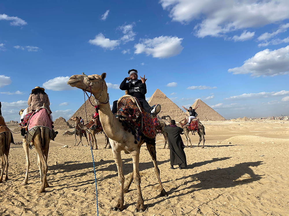 MANNY P riding camel near pyramids in Egypt